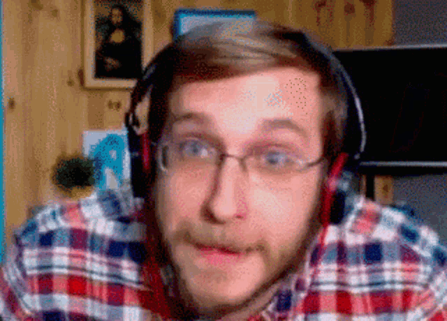 a man wearing a plaid shirt and headphones is making a funny face .