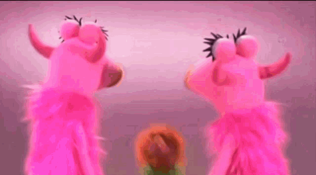 three pink stuffed animals are standing next to each other .
