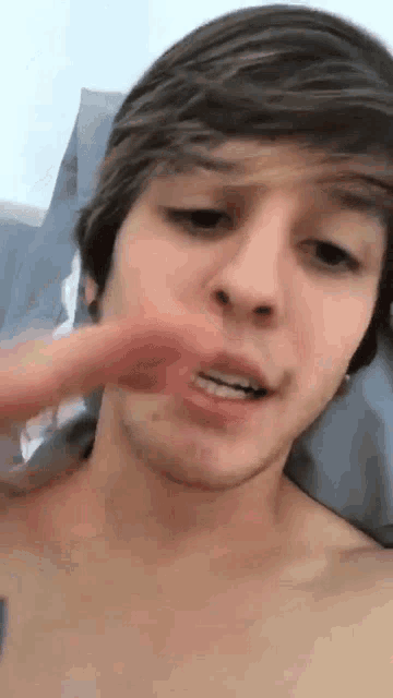 a young man without a shirt is brushing his teeth .