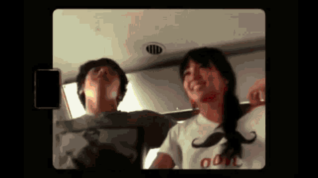 a man and a woman are standing next to each other and the woman is wearing a t-shirt with a mustache on it