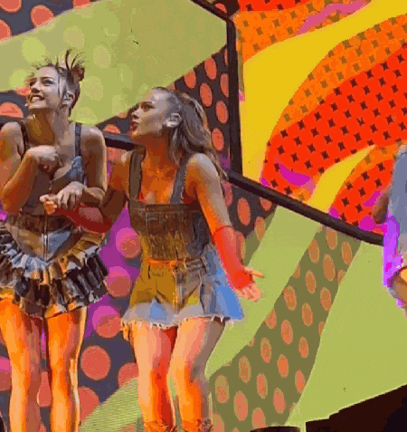 a group of women are dancing on a stage with a colorful background