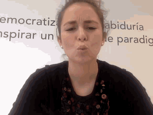 a woman blowing a kiss in front of a sign that says ' e paradig '