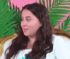 a woman with long hair is sitting in a chair with her eyes closed and a palm tree in the background .