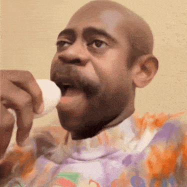 a bald man with a mustache is drinking from a cup