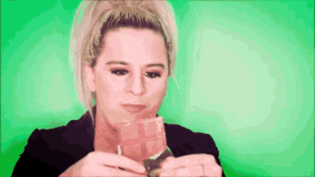 a woman in a black jacket is eating a piece of chocolate