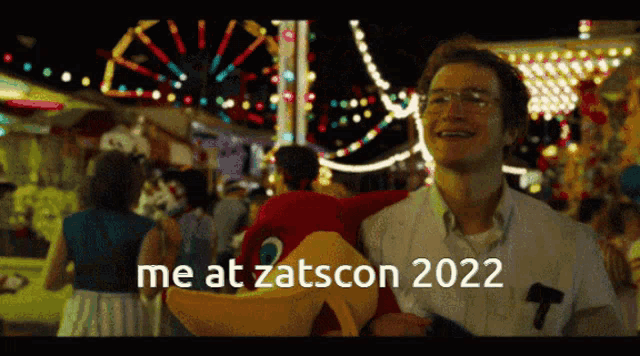 a man holding a stuffed animal with the words me at zatscon 2022 written on it
