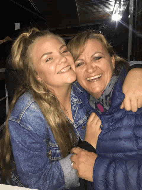a woman in a blue jacket is hugging another woman in a blue jacket