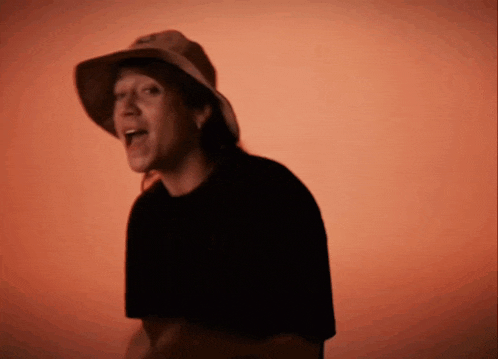 a man wearing a hat and a black shirt is singing