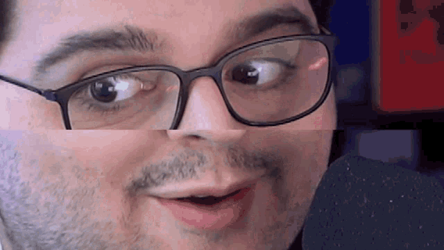 a man with glasses and a beard looks at the camera