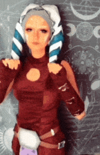 a woman in a star wars costume stands in front of a wall