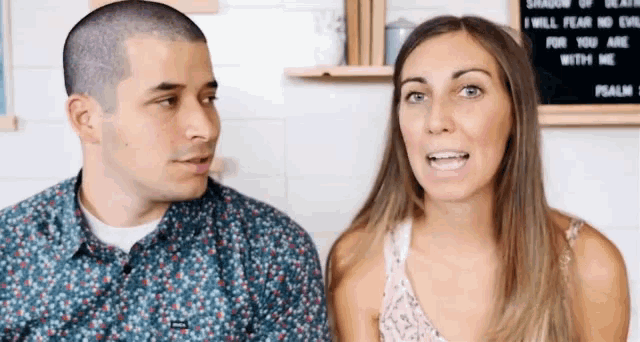 a man and a woman are sitting next to each other and talking .