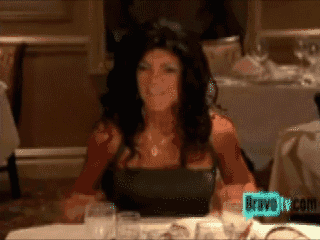a woman is sitting at a table with a bravo tv logo in the background
