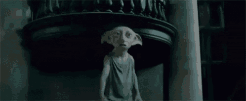 a statue of a dobby from harry potter is standing in a dark room holding a cat .