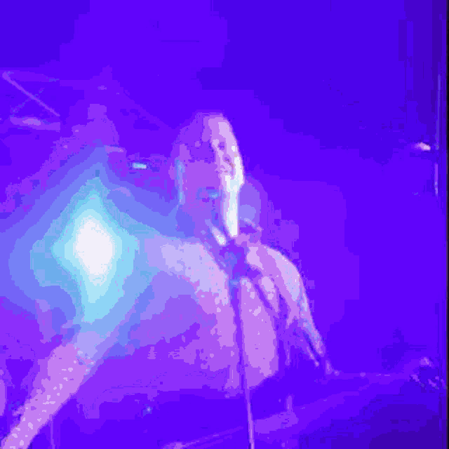 a man singing into a microphone while playing a guitar in a dark room