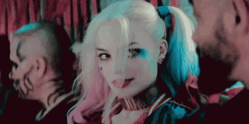 a woman in a harley quinn costume is standing next to a man in a mirror and smiling .