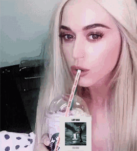a blonde woman is drinking through a straw from a cup