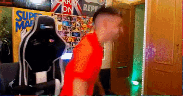 a man in a red shirt is dancing in front of a sign that says superman on it
