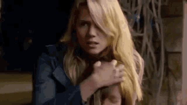 a woman with blonde hair is holding another woman 's hand .