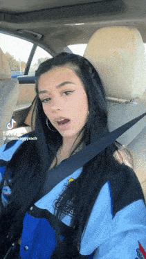 a girl is sitting in the back seat of a car with a seat belt on .