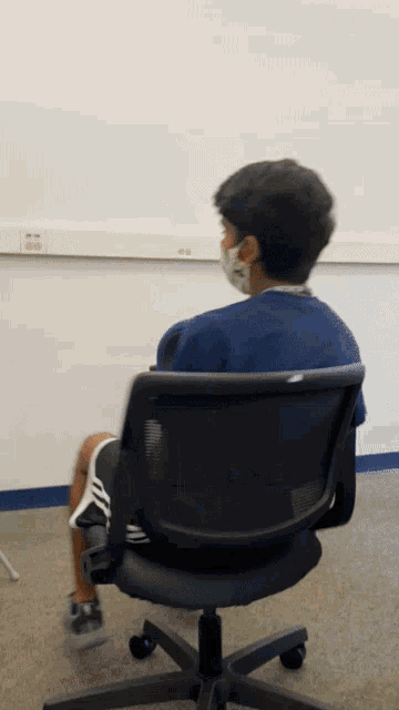 a boy wearing a mask sits in a chair