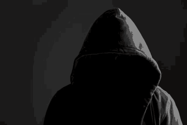 a person in a hooded sweatshirt with their face visible in the dark