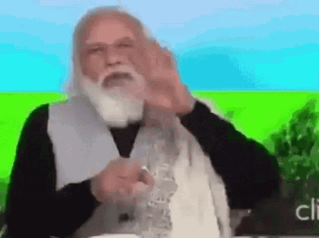 a man with a beard is sitting in front of a green screen and making a funny face .