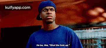 a man in a blue shirt and hat says " he be like "