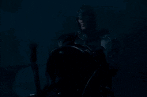 a man in a knight 's armor is holding a sword in the dark .