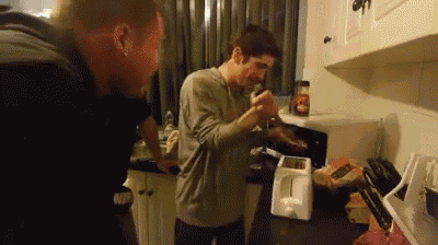 two men are standing in a kitchen with a toaster and a blender