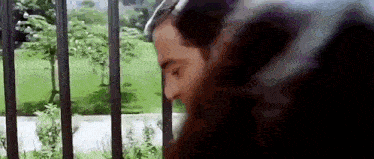 a man is standing in front of a fence looking at something .
