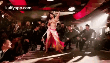 a woman is dancing in front of a crowd of people .