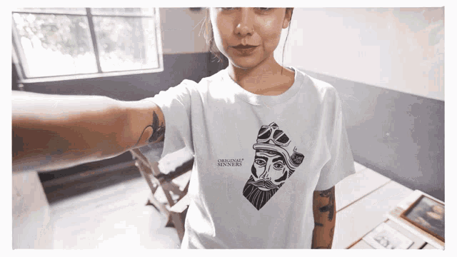 a woman is wearing a t-shirt that says " original sinners "