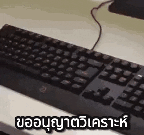 a black keyboard is sitting on top of a white table next to a computer monitor .