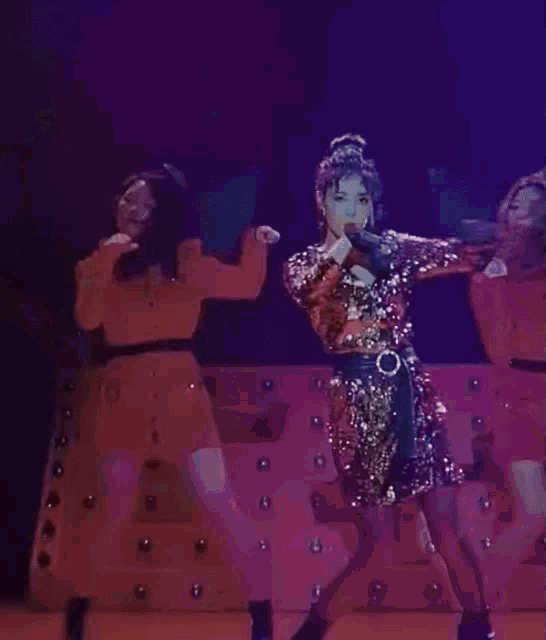 a woman in a sequined dress is dancing on a stage with other women