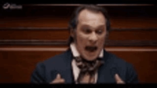 a man in a suit and tie is giving a speech in a courtroom .