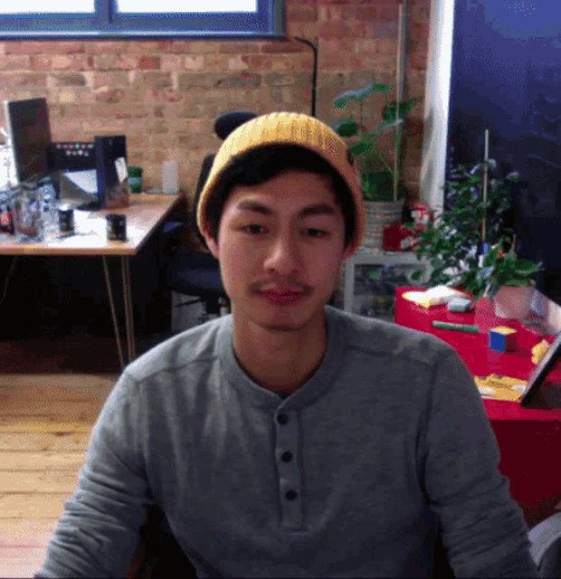 a man wearing a grey shirt and a yellow beanie