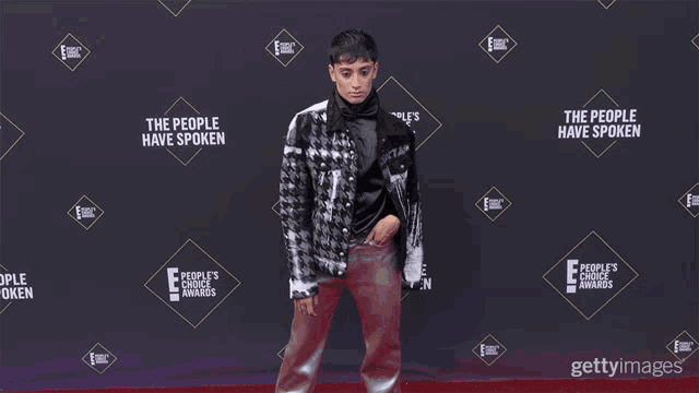 a person standing on a red carpet with a sign that says the people have spoken