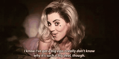a woman is laying on a bed and saying `` i know i 've got a big ego .