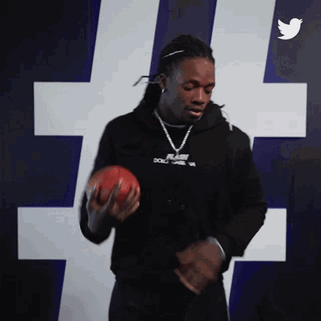 a man in a black hoodie is holding a football in his hands