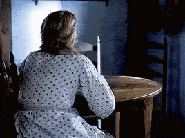 a woman in a dress is sitting at a table in a dark room .