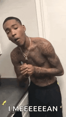 a shirtless man with tattoos is standing in front of a mirror .