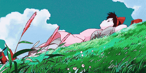 a girl in a pink dress is laying on top of a grassy hill .