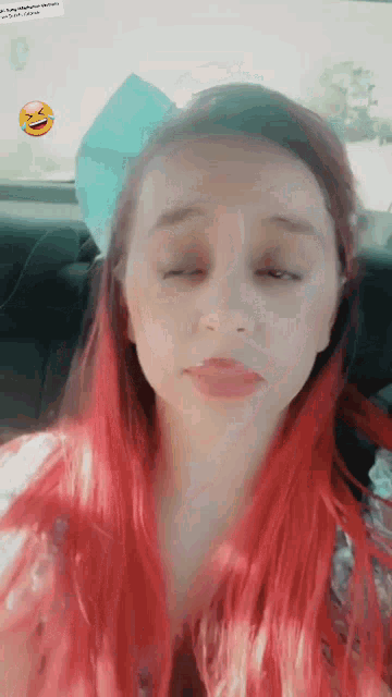 a girl with red hair is sitting in a car with her eyes closed