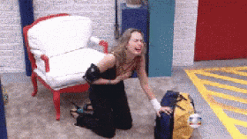 a woman is kneeling down in front of a chair and a suitcase