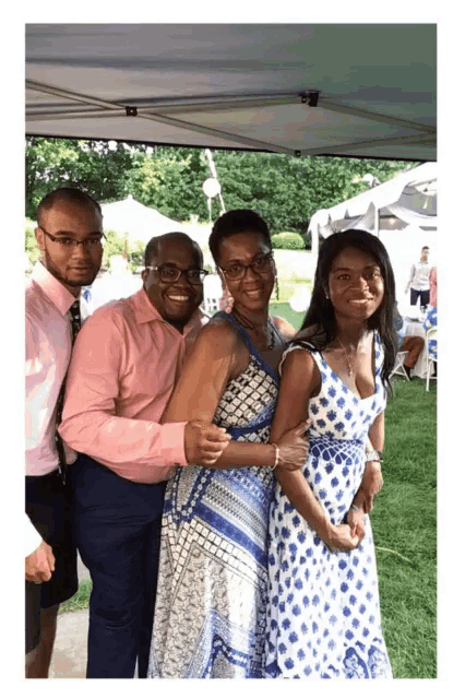 a group of people posing for a picture in front of a blue tent