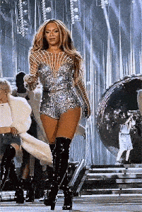 a woman is standing on a stage wearing thigh high boots and a silver dress .
