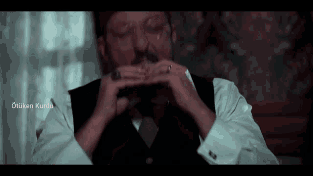 a man in a suit and tie is eating a piece of meat with the words otuken kurdu written above him