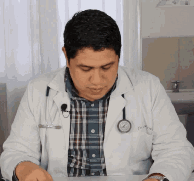 a doctor with a stethoscope around his neck is sitting at a desk with his eyes closed