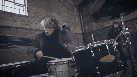 a man is playing drums in front of a window
