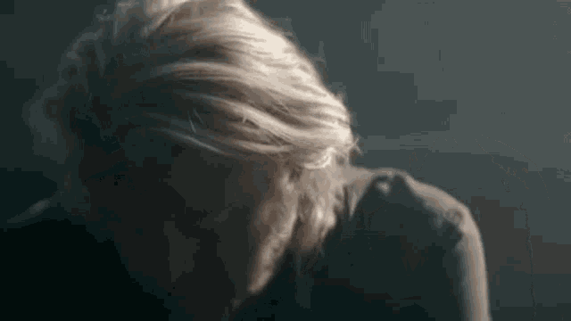 a close up of a man 's head with blonde hair in a dark room .